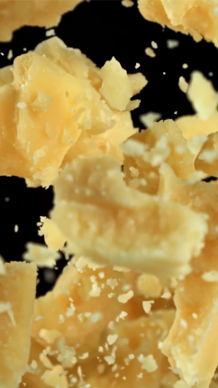 Slow Motion Parmesan Cheese Pieces Floating on Black Background