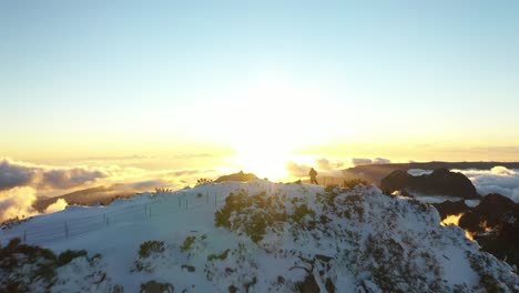 drone shot flying over a man standing by himself watching the sunset