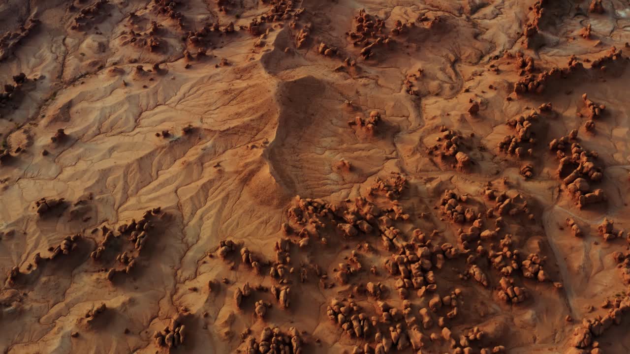 impresionante vista aérea de drones a vista de pájaro del hermoso parque estatal goblin valley utah con pequeñas y extrañas formaciones rocosas de hongos, arena seca, un lecho de río seco y rocas rojas debajo