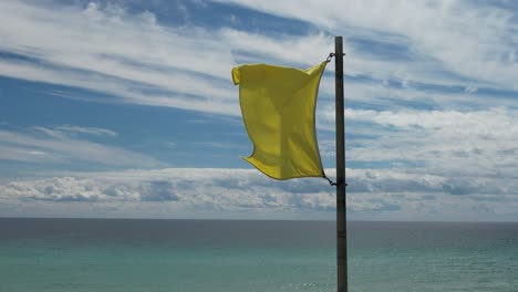 bandera de surf amarilla en un día soleado en aguas claras de esmeralda