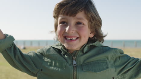 portrait of cute caucasian boy smiling happy celebrating arms raised cheerful enjoying sunny day on seaside park