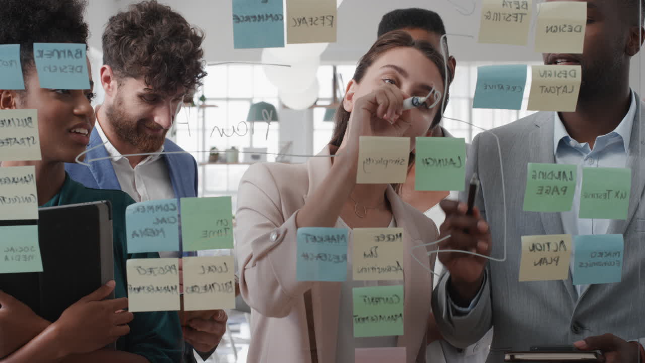 corporate business people using sticky notes brainstorming problem solving strategy on glass whiteboard team leader woman showing solution for project deadline in office meeting