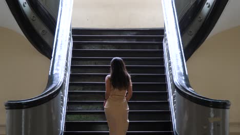 primer plano, mujer subiendo delicadamente por una escalera antigua, interior del edificio