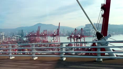 view from car on highway bridge of bustling hong kong shipping port with gantry cranes and stacked containers