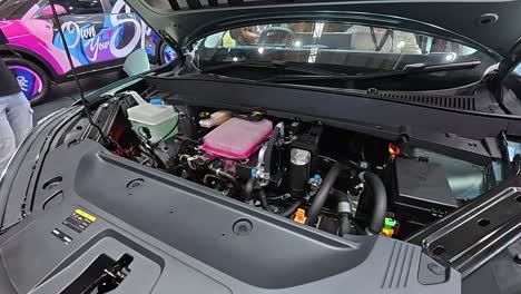 Newly revealed car engine in a showroom. The hood is open, showcasing the powerful engine to potential customers.