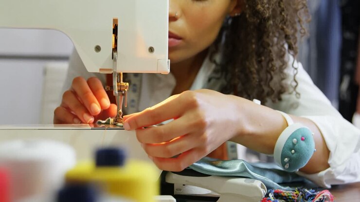 Vista frontale di una stilista di moda afroamericana che lavora alla macchina da cucire nell'atelier 4K.