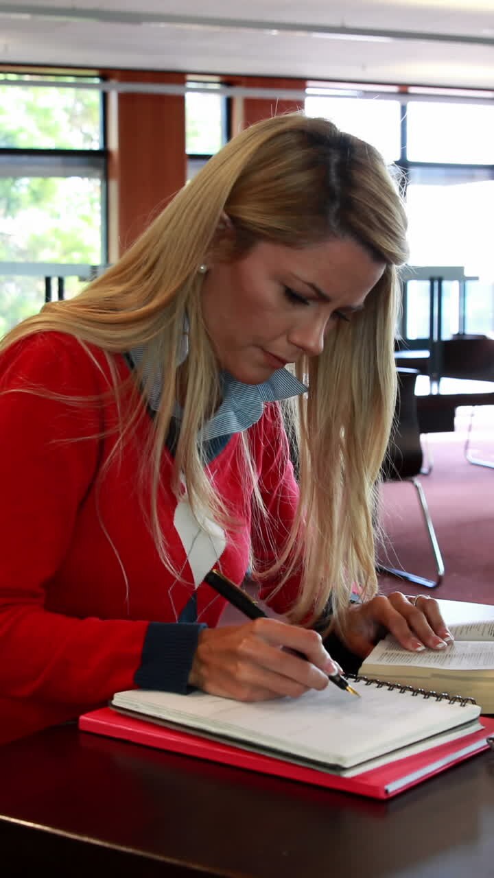 Voksen studerende med læsebriller studerer ved et biblioteksbord