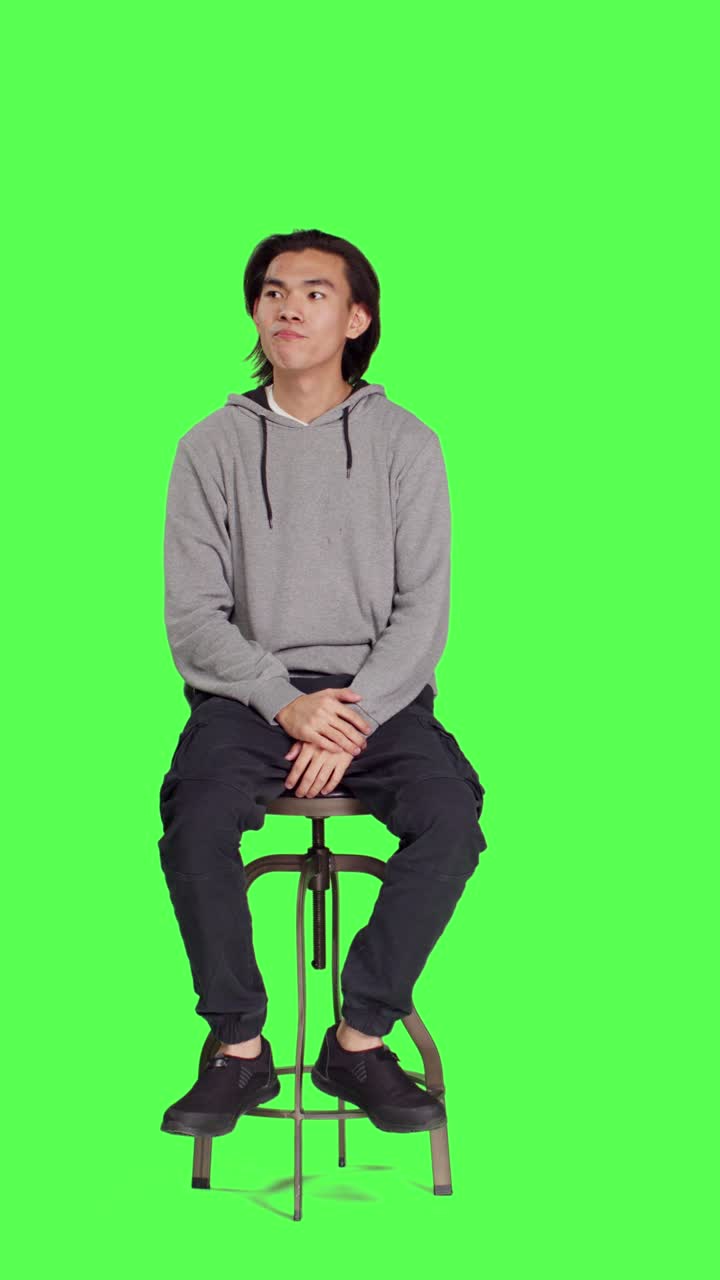Vista frontale di giovane adulto seduto su una sedia in attesa