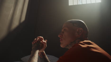 tattooed inmate begging for forgiveness during prayer in prison cell