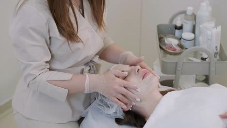 cosmetologist doing face treatment and applying face mask