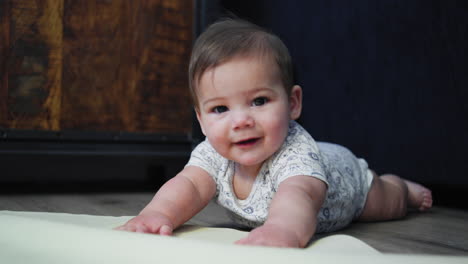 baby boy smiling on the ground while on his stomach learning how to crawl