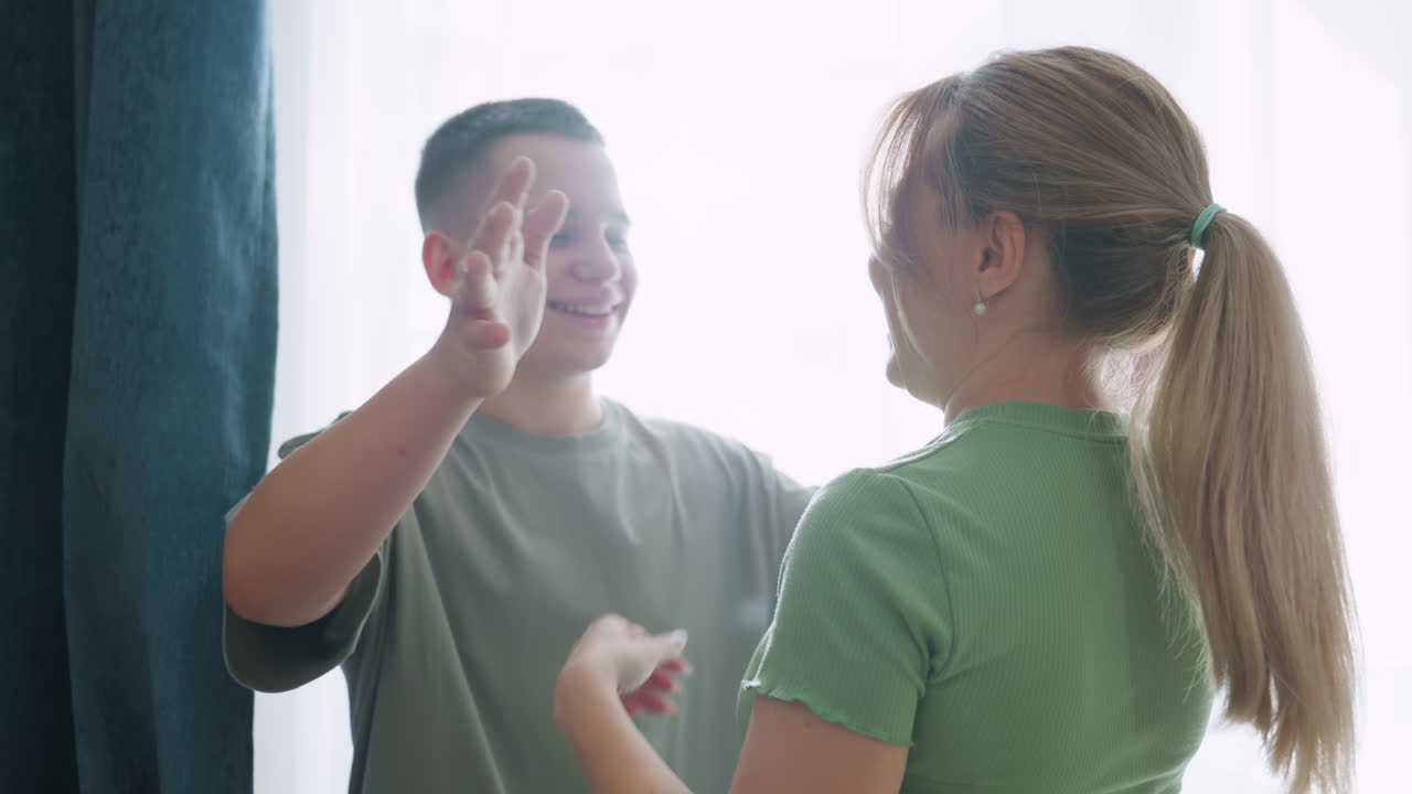 Mother discovers youngster hiding behind curtain during hide and seek, touches nose with gentle gesture, laughter turns into hug, sunlight through window highlights warmth of playful family bonding