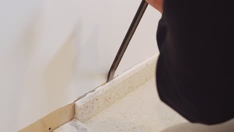 Extreme-closeup-on-skirting-tiles-being-removed-with-flat-pry-bar