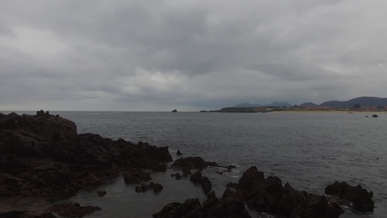 Rocky coast of Playa de Quejo in Cantabria, with a view of San Pedro Islet