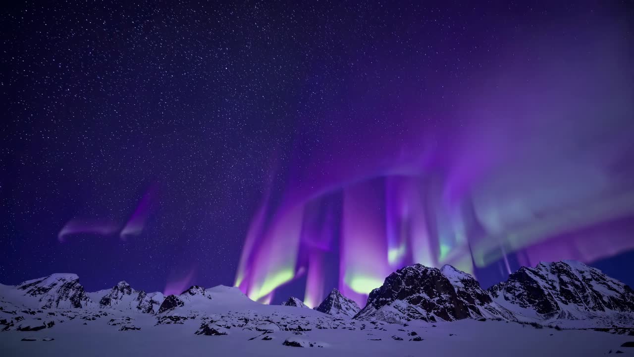 A wide-angle video captures vibrant auroras dancing over snow-capped mountains under a starry sky