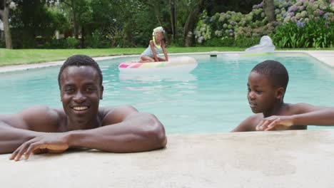 happy african american father and son relaxing in pool