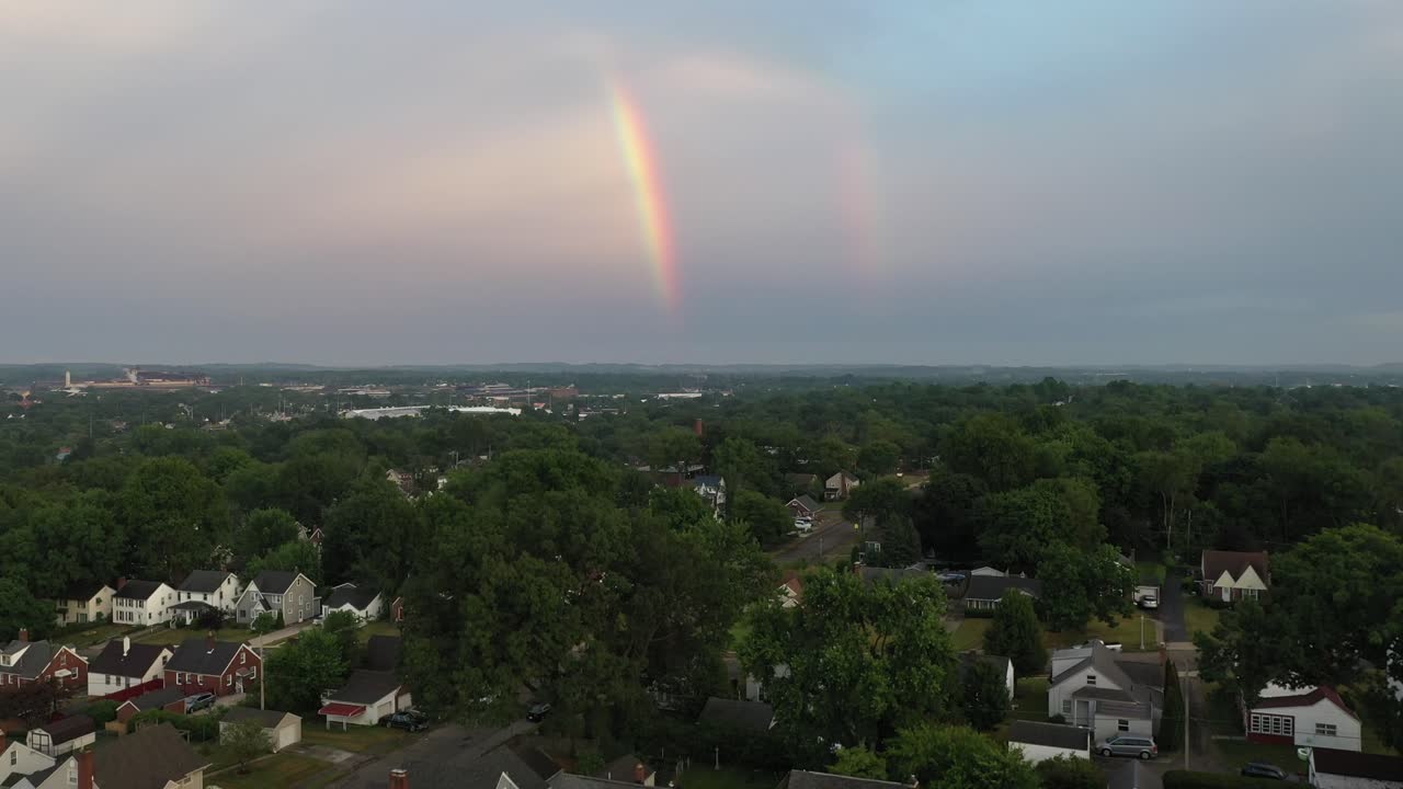 disparo de un dron de un arco iris sobre una ciudad al atardecer