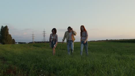 three women walking in a field at sunset