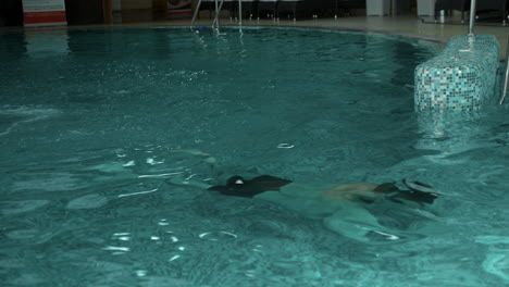 Athletic-body-guy-swimming-underwater-in-pool.-Handsome-man-relaxing-in-spa.