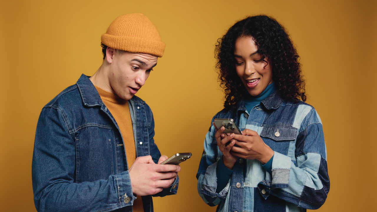 Two friends laughing and using their phones