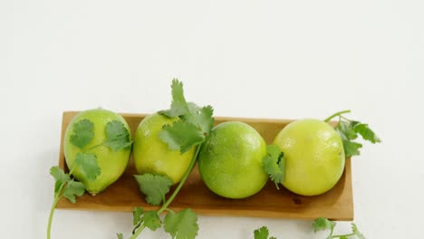 frutas de lima en una bandeja con hoja de cilantro 4k
