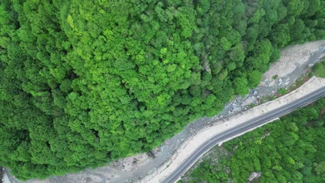 Top-View-Of-A-Rural-Road-In-Dense-Forest-Valley-And-River-Near-Lepsa,-Vrancea-County,-Romania