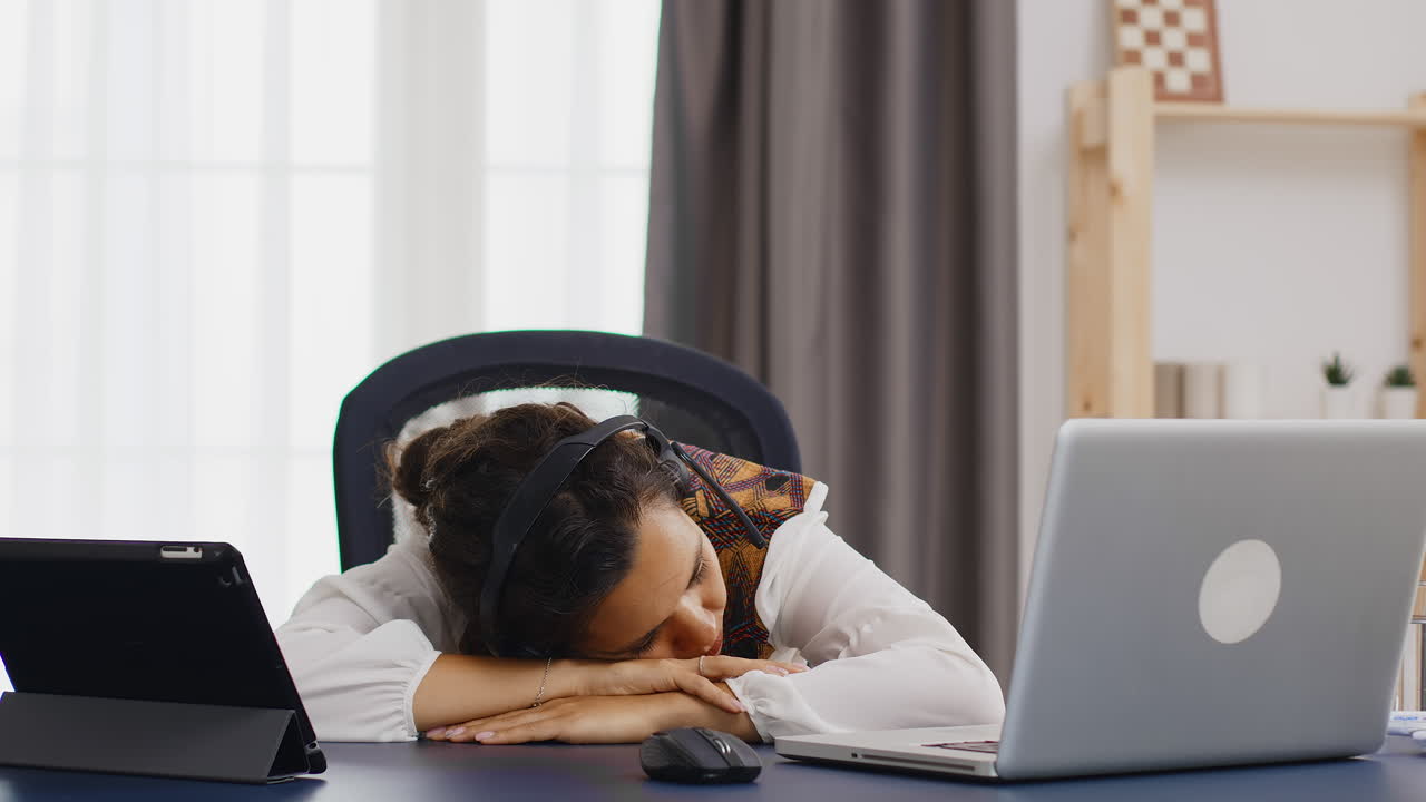 책상 위에서 잠을 자고 있는 집에서 일하는 피곤한 여자