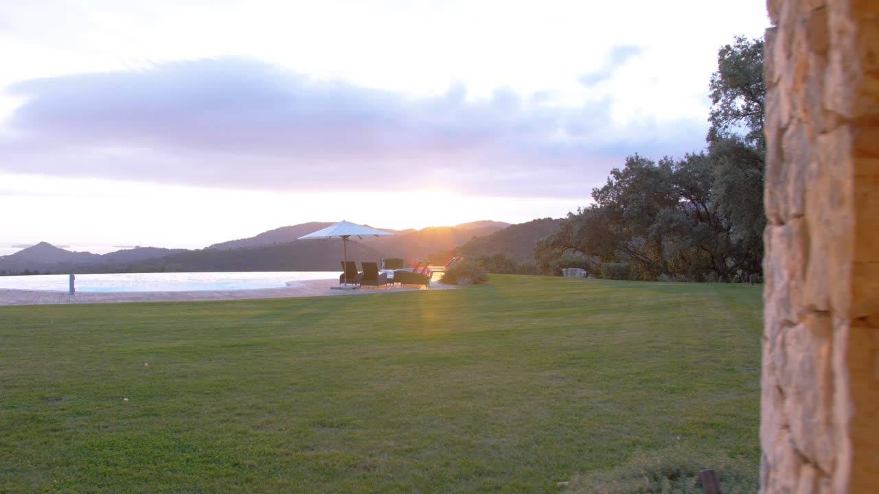 un impresionante amanecer sobre una montaña en la distancia, visto desde una villa de lujo con piscina infinita y columnas de piedra en cannes, al sur de francia