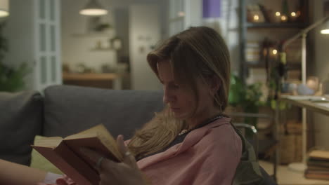 woman reading book on sofa at home