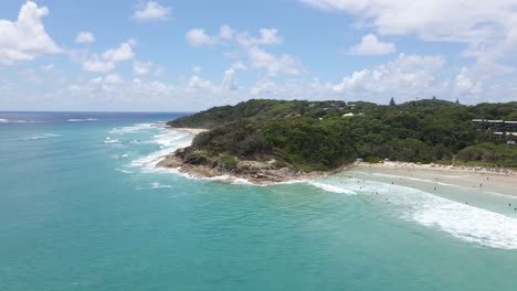 Tourists-Swimming-At-Summer-Beach-By-The-Lush-Foliage-Landscape-Of-Cylinder-Headland-Foreshore-In-Point-Lookout,-Australia