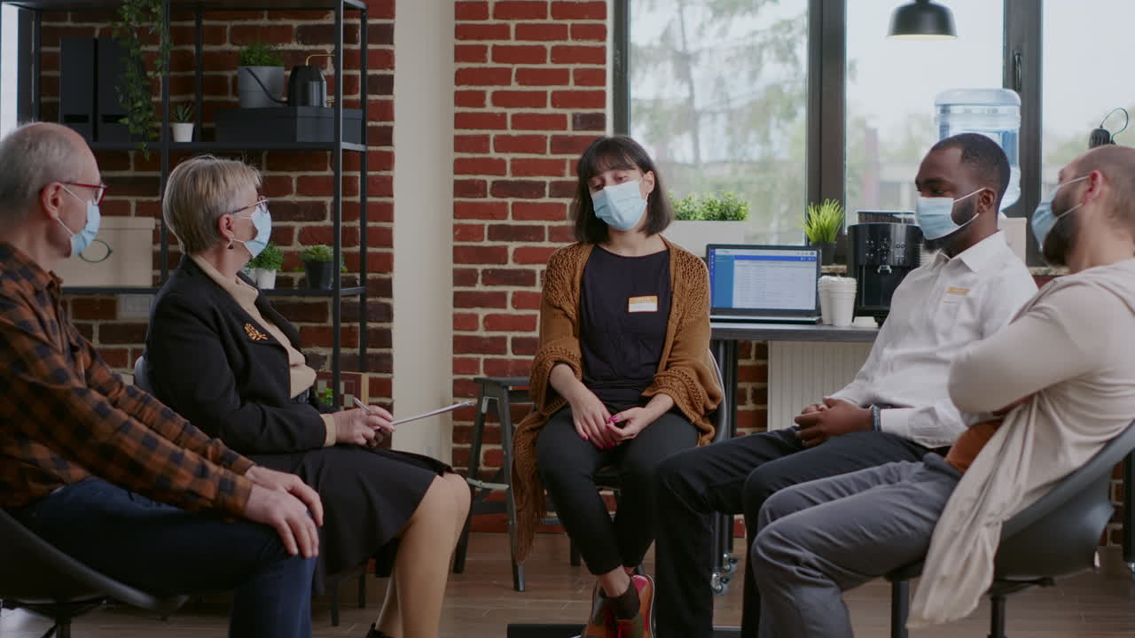 Sad woman making confession in front of people at aa therapy session during pandemic