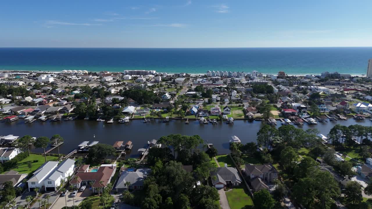 Panoramic drone fly of dense suburban neighborhood with water canals and houses towards the ocean, Panama City Beach, Florida, USA