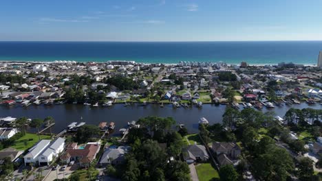 panoramic drone fly of dense suburban neighborhood with water canals and houses towards the ocean, panama city beach, florida, usa