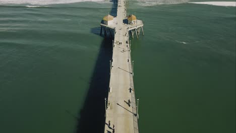 Vista-De-Drones-Desde-La-Playa-Hasta-El-Final-Del-Muelle-De-Huntington-Beach-En-Un-Impresionante-Hiperlapso,-Que-Muestra-El-Océano-Pacífico-Y-El-Edificio-Del-Techo-Rojo