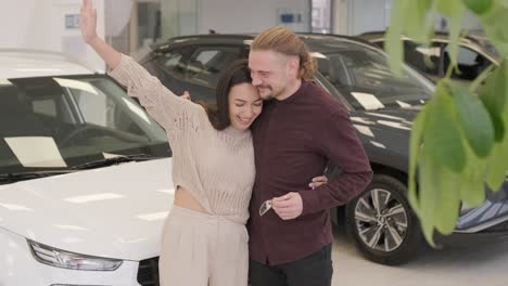 una hermosa pareja de jóvenes en la sala de exposición de automóviles eligiendo un coche nuevo para comprar.
