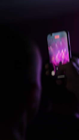 smartphone capturing vibrant concert performance with colorful lights and energetic atmosphere