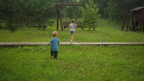 girl runs to playground and toddler boy follows sister