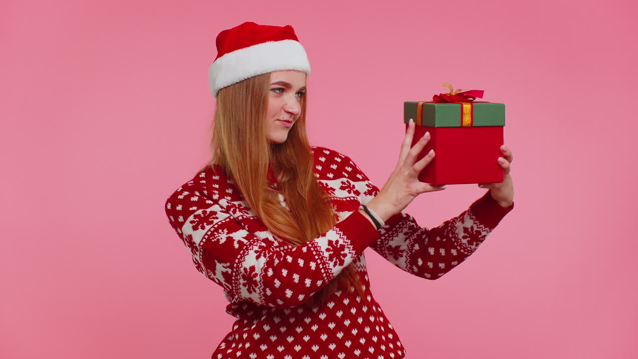 chica feliz usa suéter de navidad rojo recibió un regalo, interesado en lo que dentro de la caja de regalos