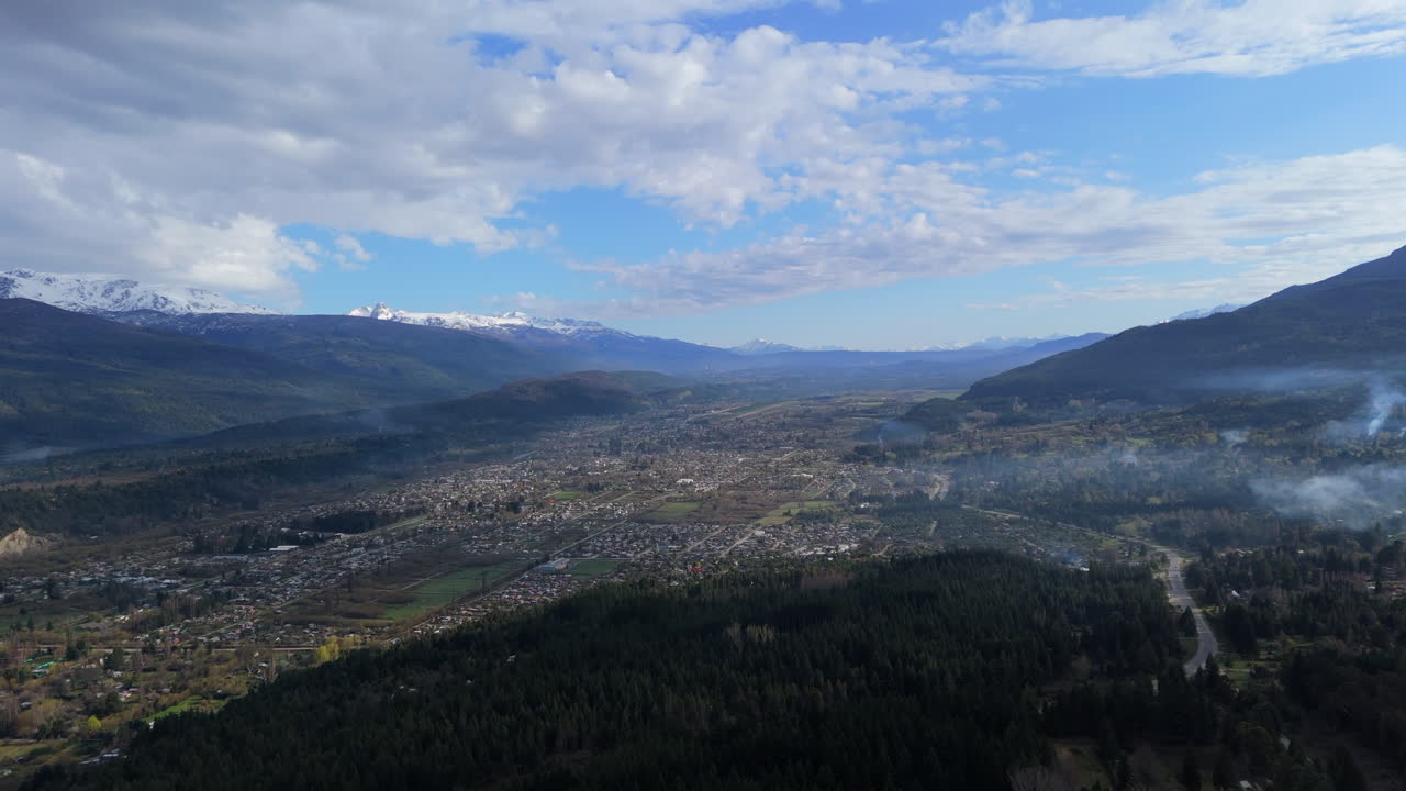 초록색 과 눈 인 산맥으로 둘러싸인 푸른 하늘 아래의 "엘 볼슨"을 보여주는 고해상도 드론 영상입니다.