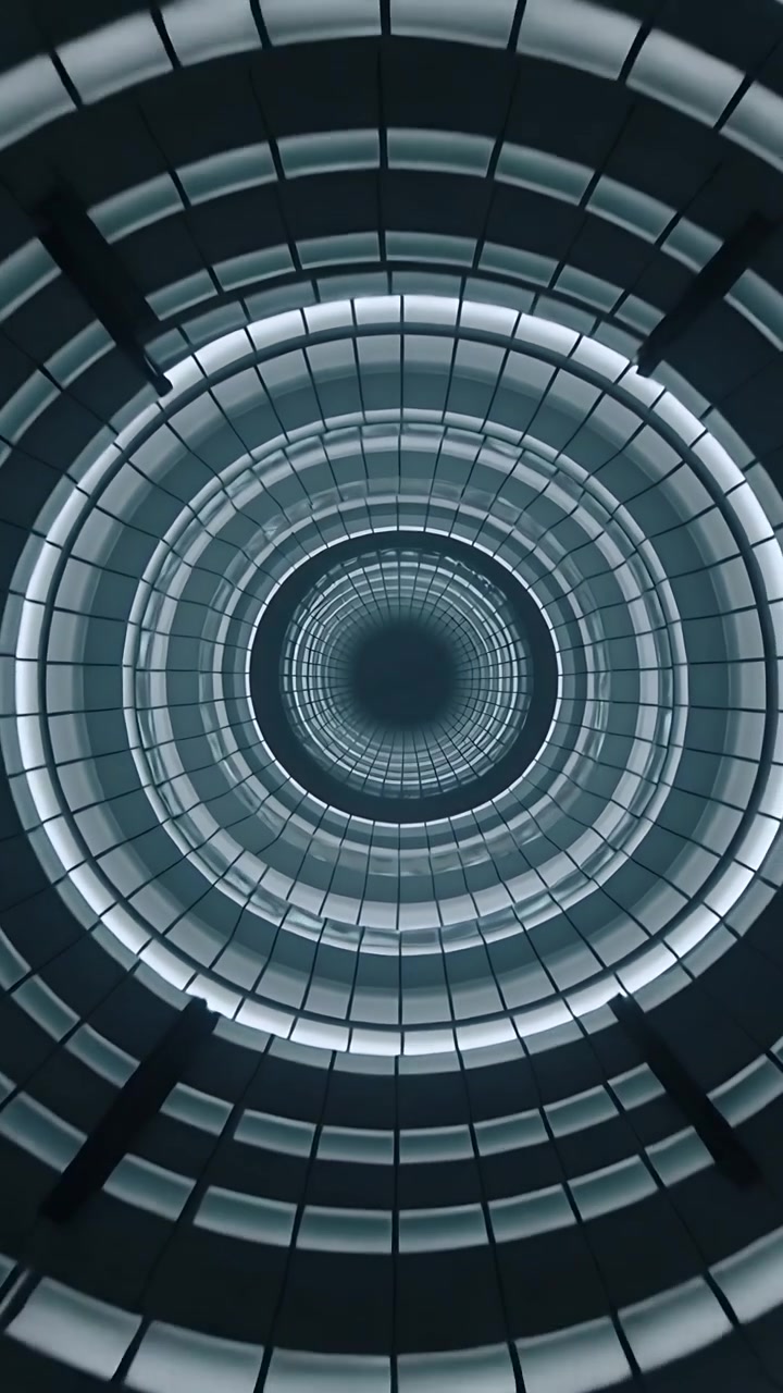 Video verticale: La telecamera si allontana rivelando un pozzo atrio circolare, che espone anelli luminosi concentrici.