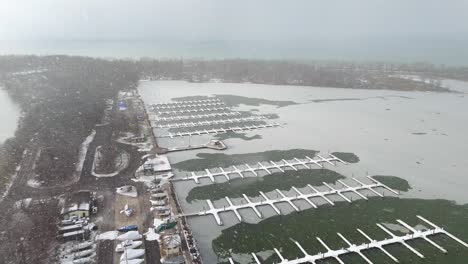 aerial shot pulling out from snow falling on a boat dock at presque isle state park.