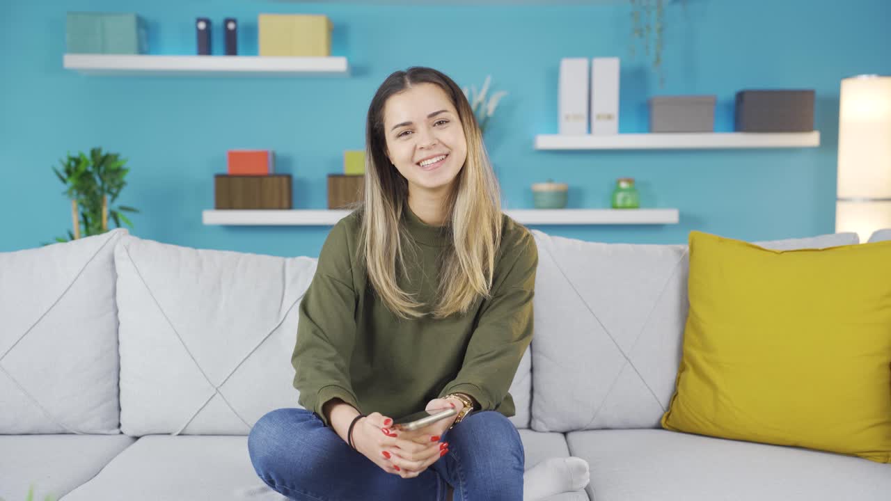 유쾌한 젊은 여성이 카메라를 향해 미소 짓습니다.