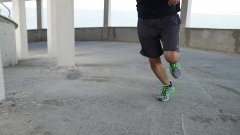 unrecognizable athlete runs around by levels of and empty parking garage, front view