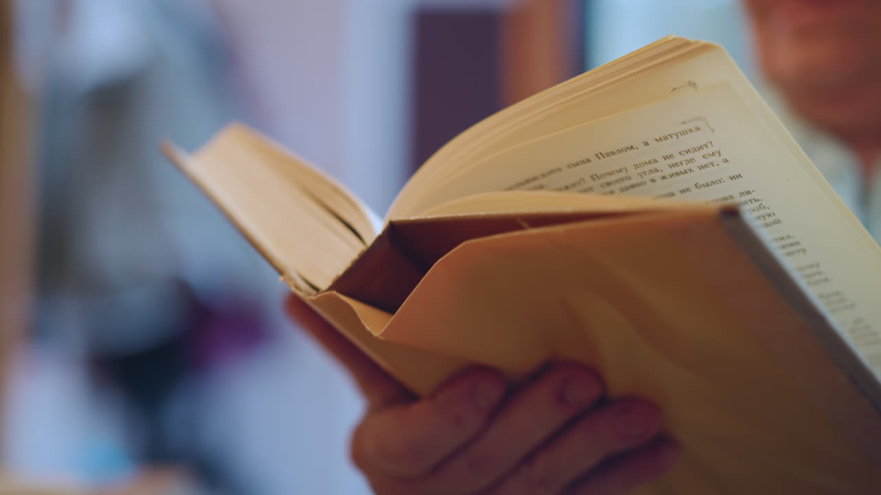 Donna anziana che legge. Donna anziana con un libro sotto una luce calda. Anziana signora che tiene un libro ben usato in un ambiente accogliente. Anziana signora che si gode il suo tempo con un libro classico in un'atmosfera interna calda