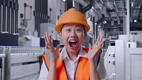 close up of asian female engineer with safety helmet smiling to camera and saying wow with water production in bottling factory