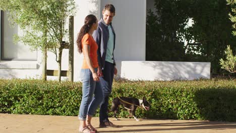 una feliz pareja caucásica está llevando a su perro a pasear