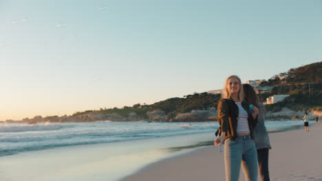 Freundinnen-Blasen-Am-Strand-Bei-Sonnenuntergang-Seifenblasen-Und-Haben-Spaß-Im-Sommer,-Spielen-Am-Meer-Und-Genießen-Die-Freundschaft