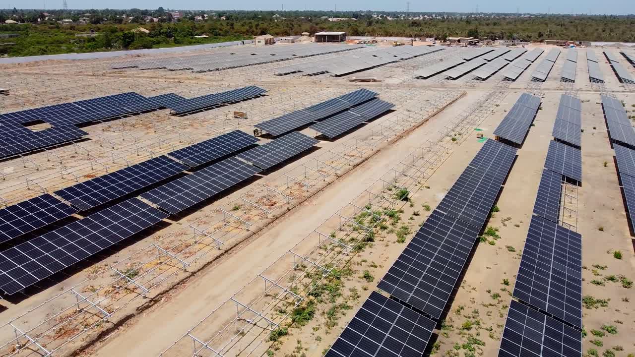 Aerial tracking shot over unfinished sunlight collectors at a solar energy plant
