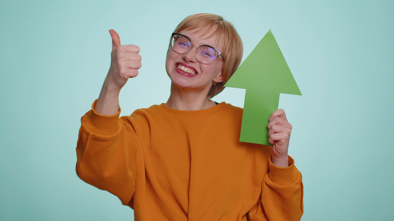 Happy woman winner holding arrow sign pointing up career growth and money increase good progress