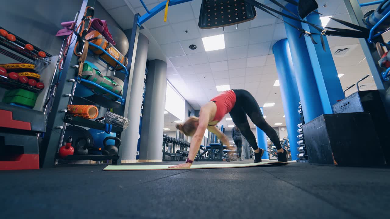 Sports workout in the gym. Young woman in sports suit is doing exercises on the mat in the modern fitness club.